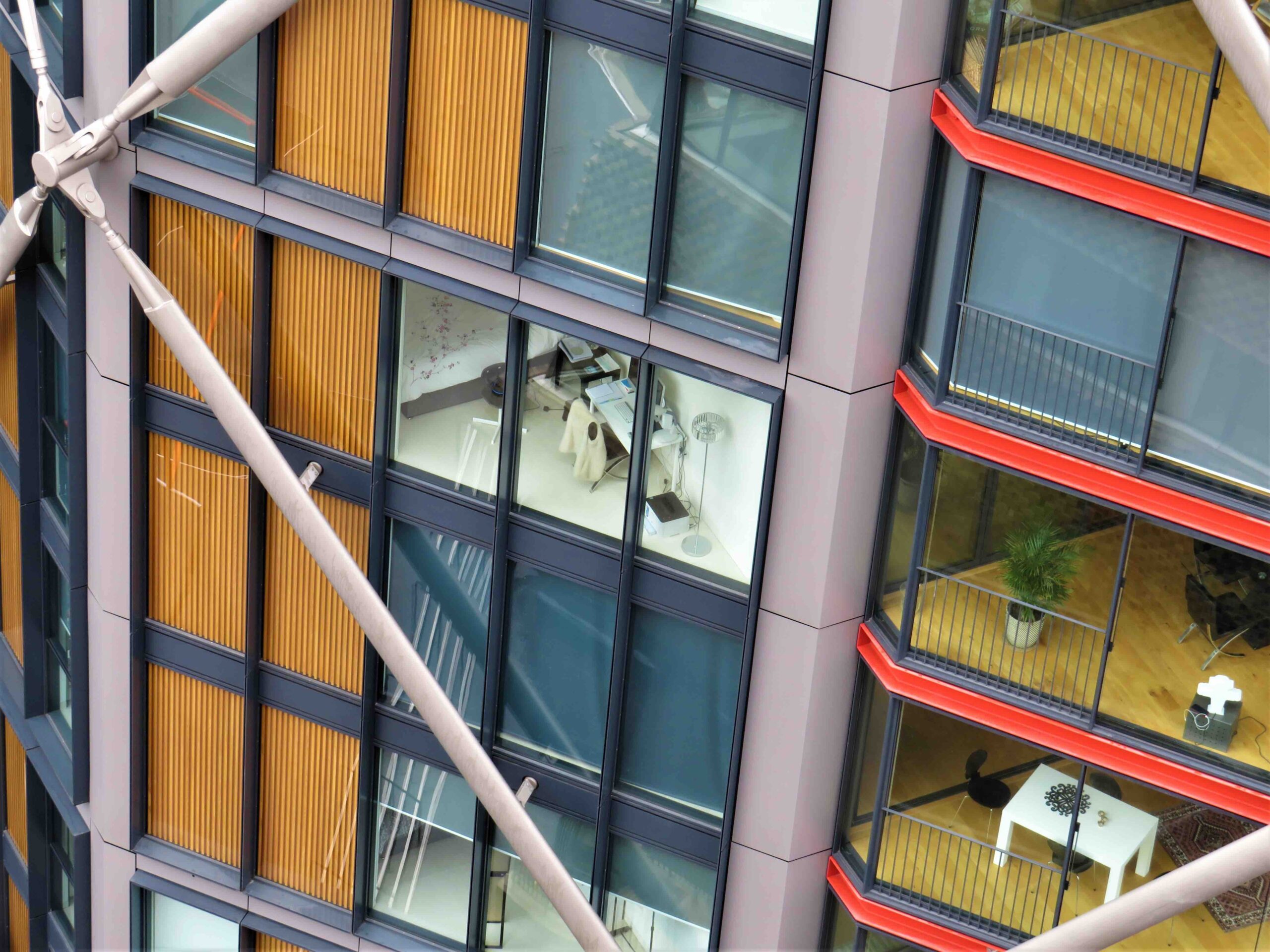 Modern office building exterior with red balcony accents seen from below.