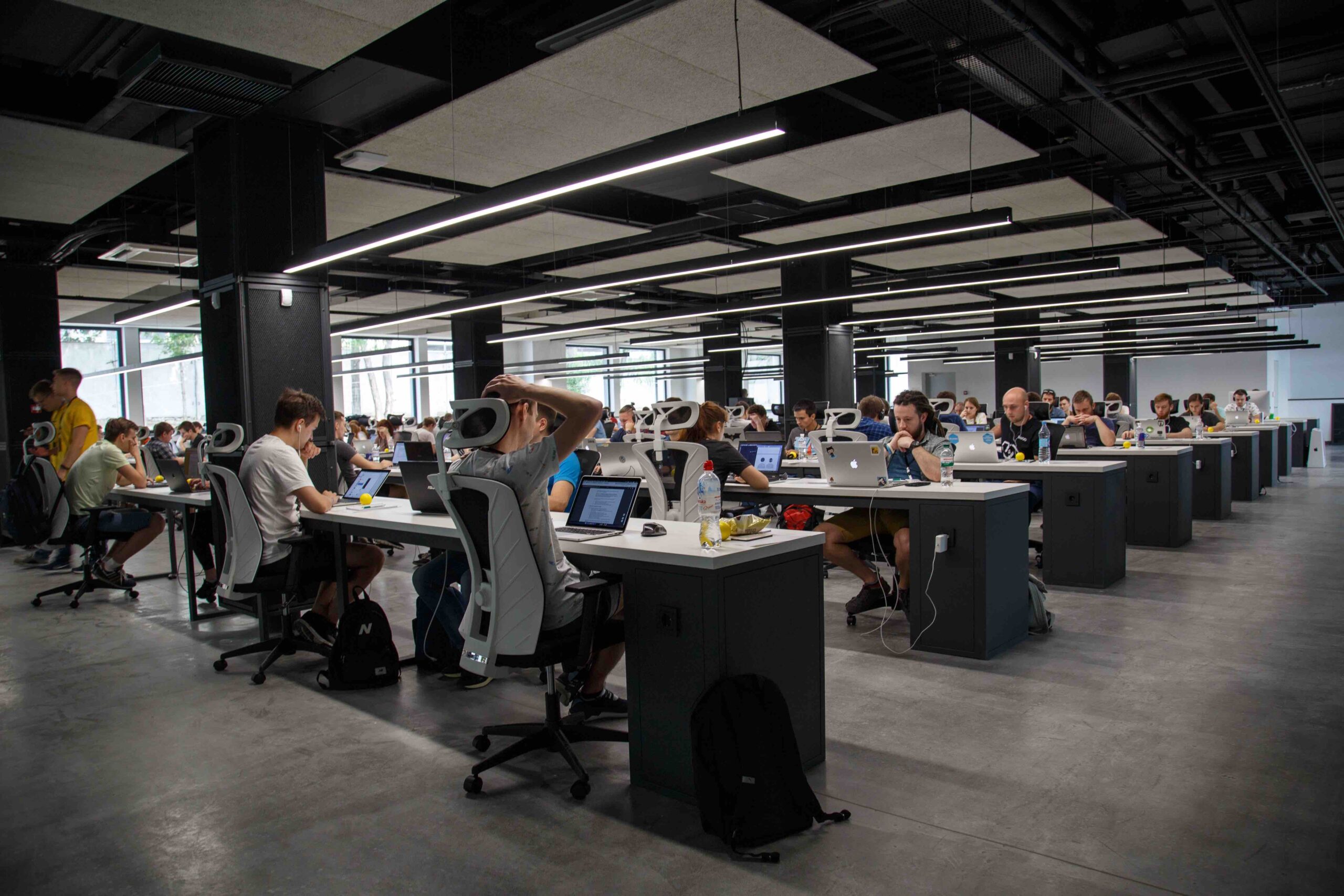 Open coworking office with rows of desks, computers, and professionals at work.